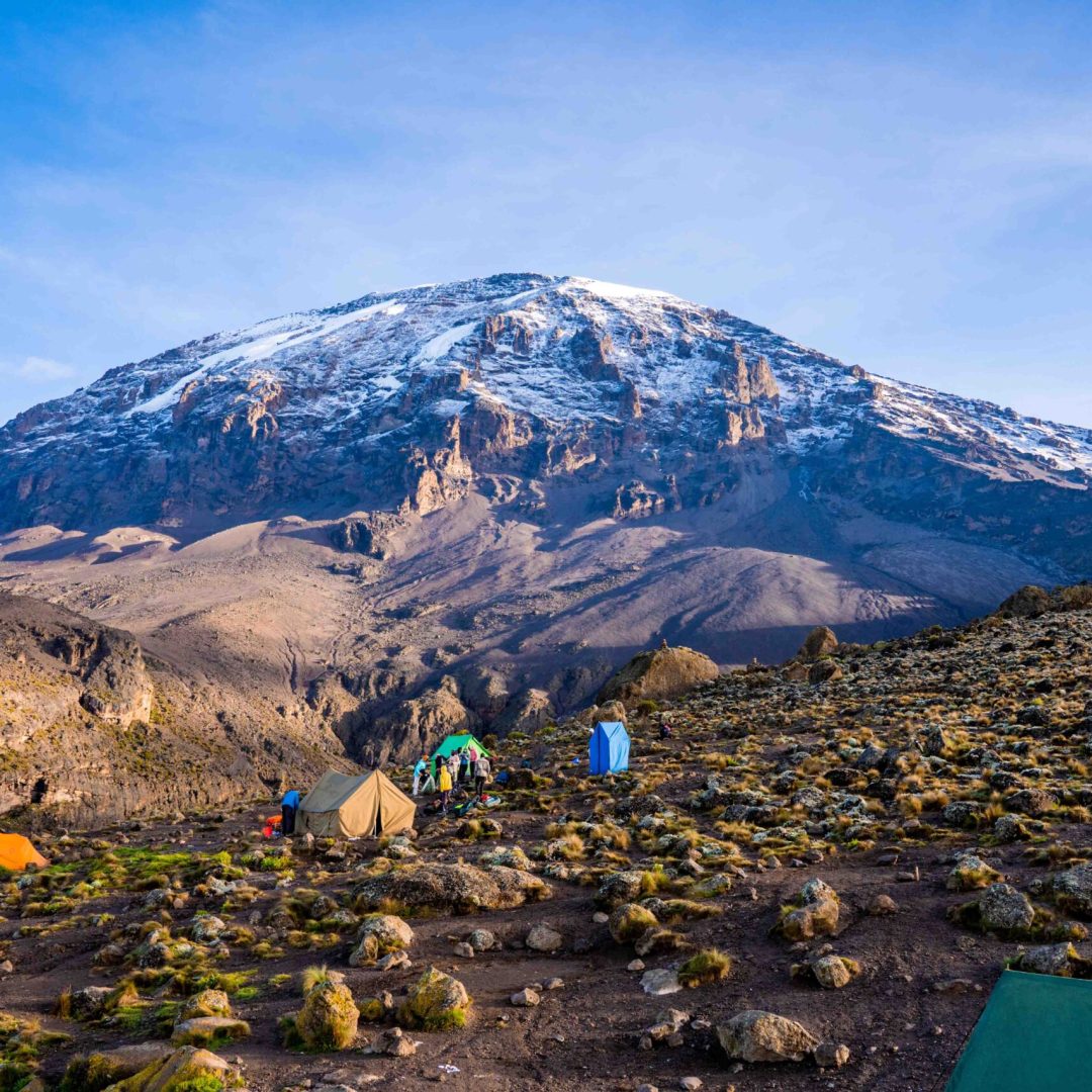 Camping on mount Kilimanjaro in tents to see the glaciers in Tanzania, Africa Orange tents on the way to Uhuru Peak.